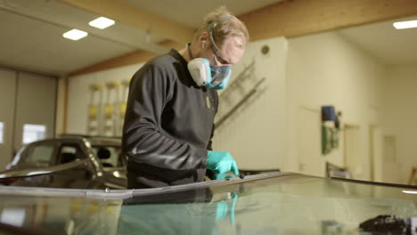 workshop technician applying primer for adhesive on car windshield