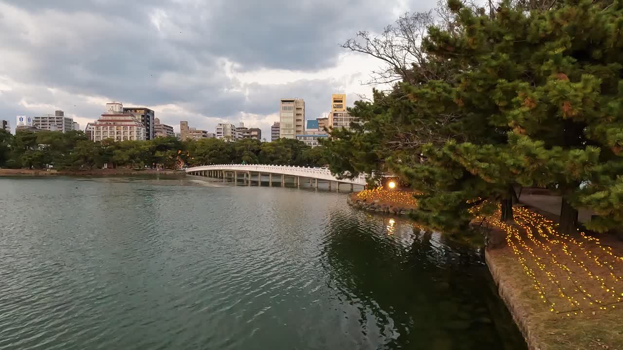 vista sobre el horizonte de fukuoka ante el estanque en el parque ohori, por la noche con luces de navidad