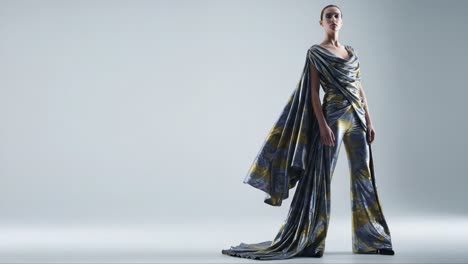 stunning fashion showcase: a model exudes elegance in a flowing metallic ensemble with unique patterns and dramatic draping in a minimalist setting