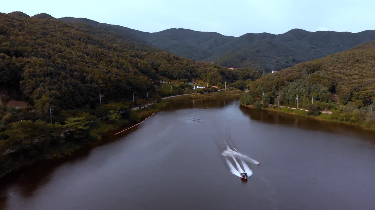 Backwards aerial view of a speedboat with jet skier starting seen from the front