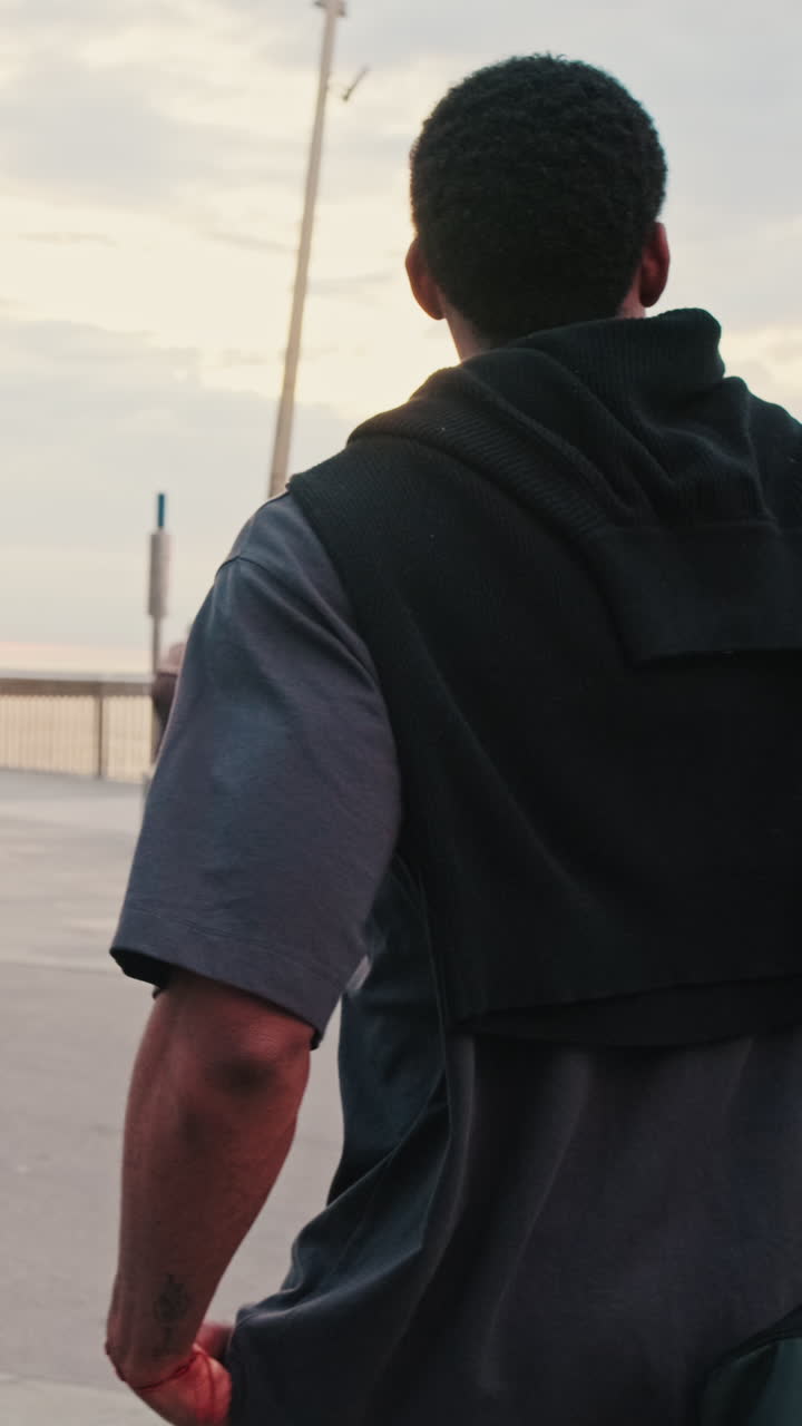 Young Man Walking on Promenade Looking at the Sea at Sunset