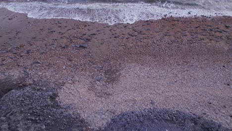 Drone-shot-flying-down-a-cliff-towards-the-sea-with-waves-crashing-on-the-beach,-Jurassic-Coast,-Dorset,-UK