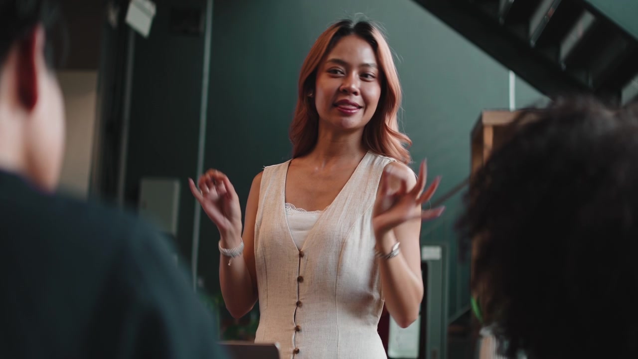 Giovane donna che tiene una presentazione ai colleghi in un ufficio moderno.
