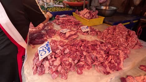 person organizing fresh meat cuts on display