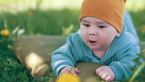 lovely kid in a good mood lying on a pillow in the grass. beautiful child looking curiously around. close up.