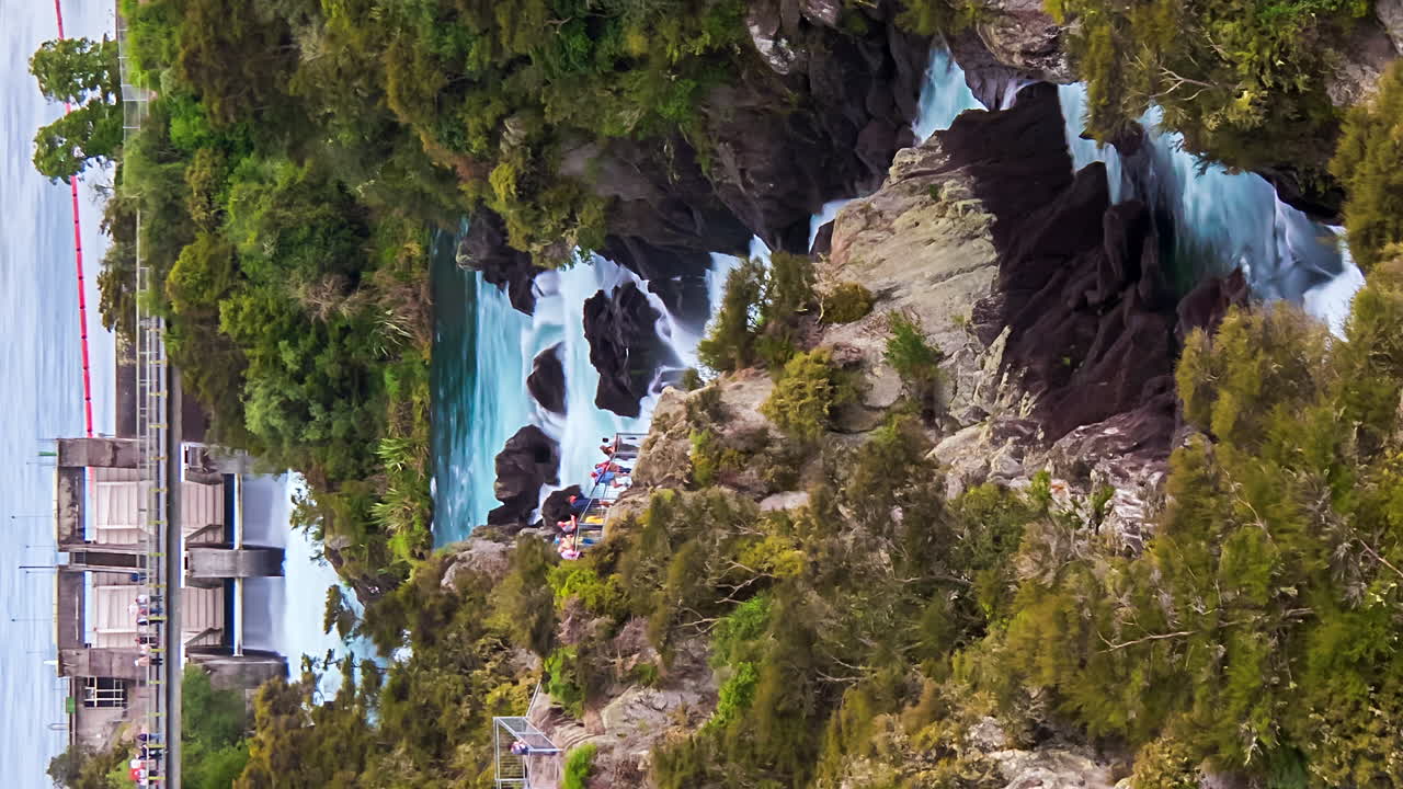 Turisti osservano il rilascio dell'acqua dalla diga di Aratiatia che scorre verso il lago, orientamento verticale