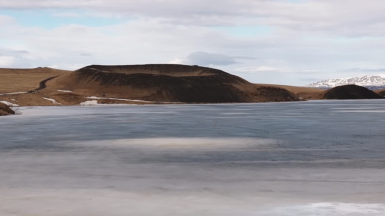 Aerial view of Vestrahorn mountain and the dramatic black sand beach at Stokksnes Peninsula, Iceland. Coastal beauty meets volcanic terrain under cloudy skies.