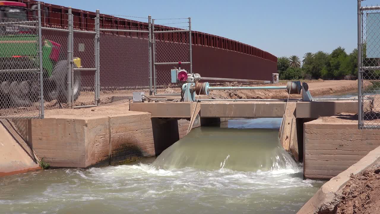 un tractor de agricultores sigue un afluente del río colorado a medida que fluye a lo largo del muro fronterizo entre los estados unidos y méxico 1