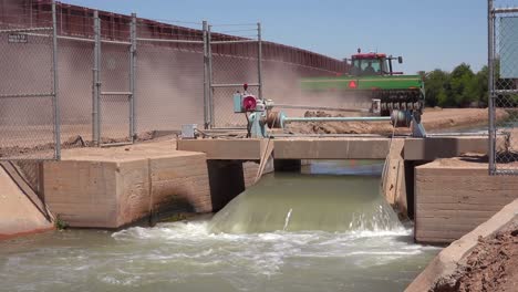 Ein-Farmer-Traktor-Folgt-Einem-Nebenfluss-Des-Colorado-River,-Der-Entlang-Der-Grenzmauer-Zwischen-Den-USA-Und-Mexiko-Fließt-1