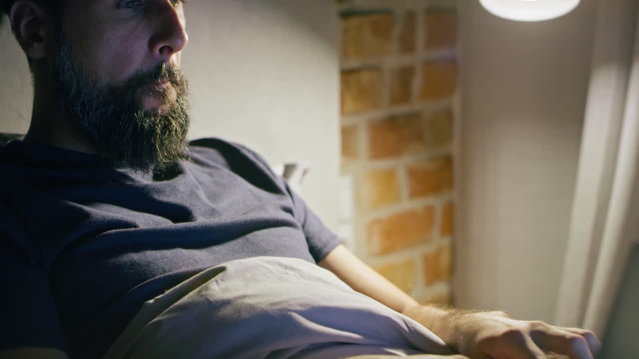 Video man lying in bed and working at night