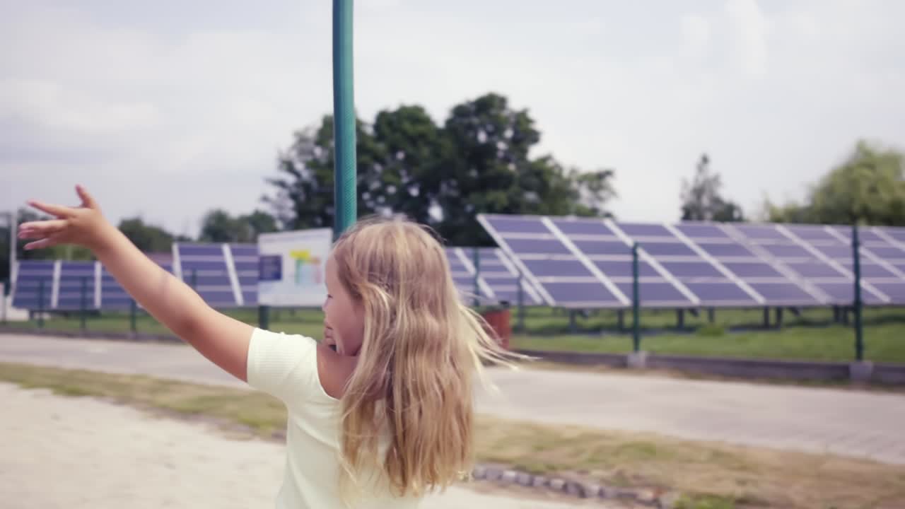 una chica rubia feliz con el cabello largo ondea a la cámara mientras pasa por el teleférico de los niños