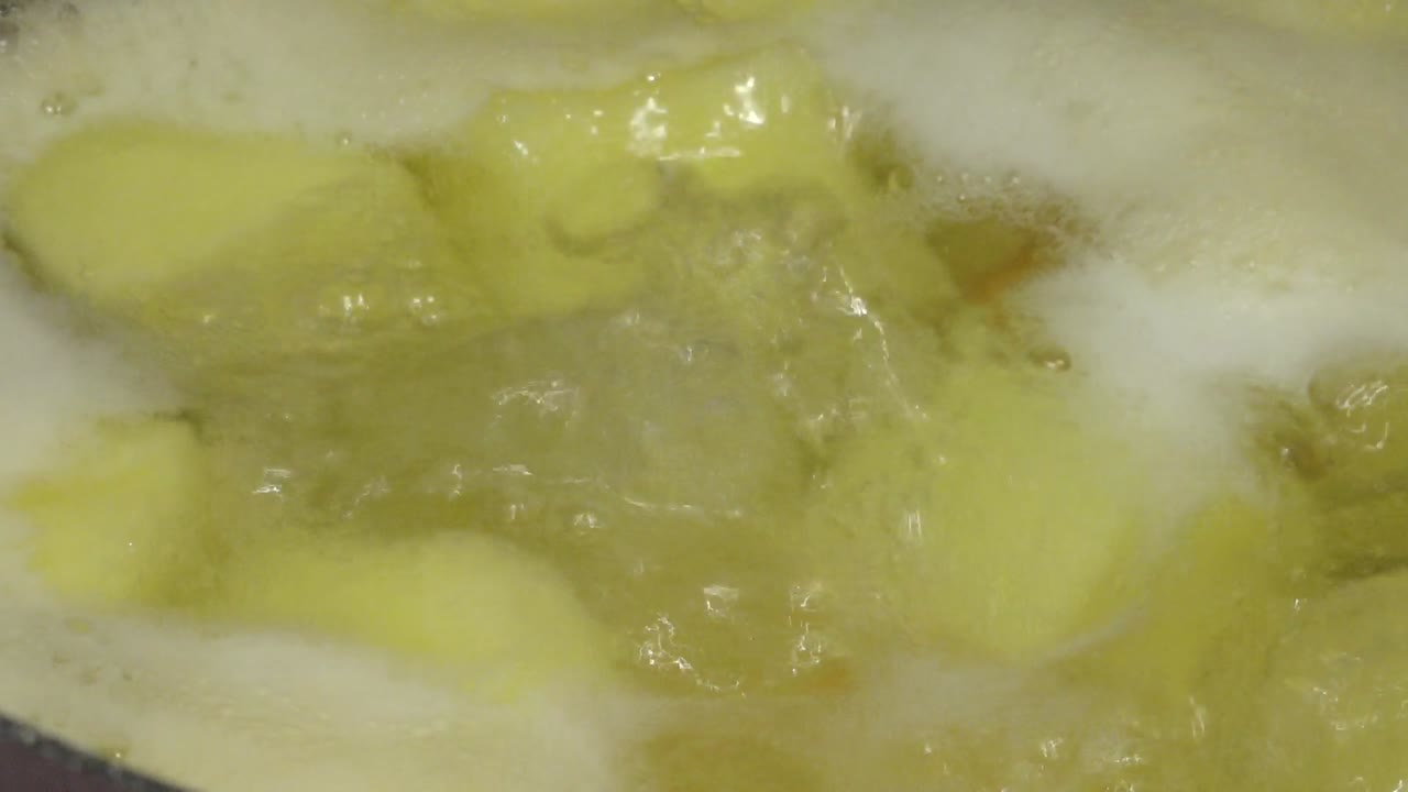 Chunks of potatoes and vegetables boiling in a pot of water, forming the base for a hearty homemade soup or stew