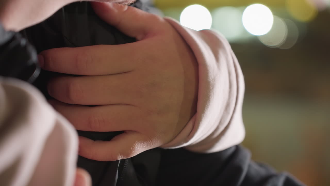 Close up of lady gently holding man with light mustache from behind as her hair drops softly in front of urban night lights, capturing tender moment with glowing background