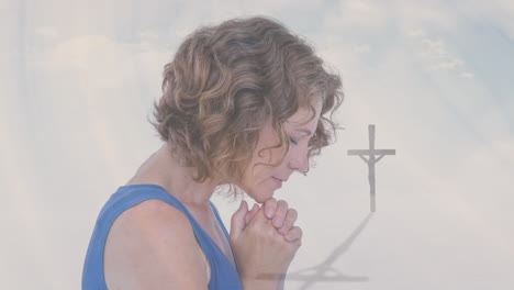 mujer orando sosteniendo una cruz con nubes animadas en el fondo