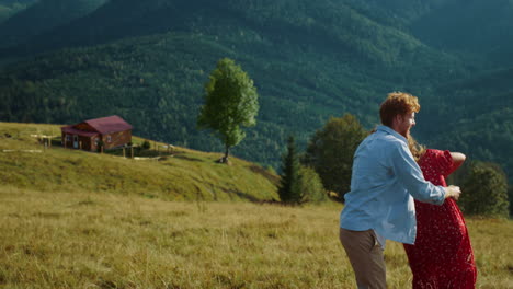 young family dance together in summer mountains. smiling couple have fun outside