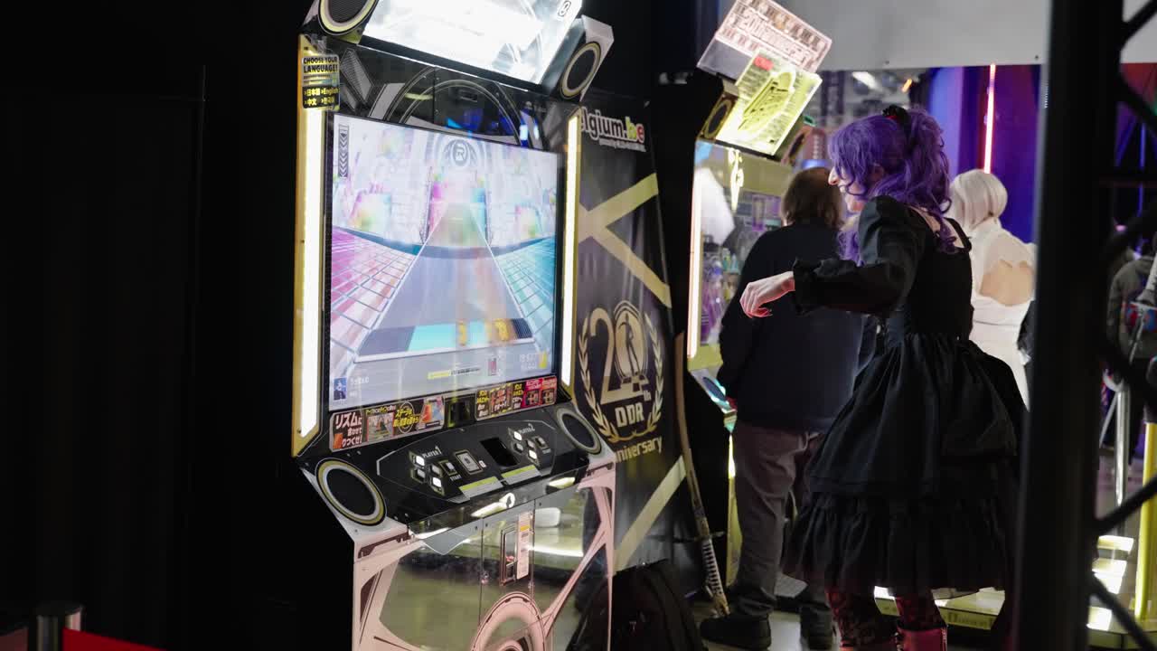 Girl with purple hair and black dress costume cosplayer dancing on a electronic gaming machine revolution having fun collecting points at a convention event at LGX Luxembourg