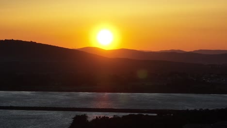 Sun-setting-behind-the-Mediterranean-Pyrenees-near-Manguelone-France,-Aerial-dolly-out-shot