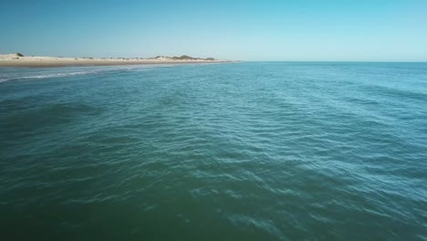 aerial, low angle flyover of water on approach to isolated beach of barrier island on the texan gulf of mexico coast on a bright sunny afternoon - south padre island, texas