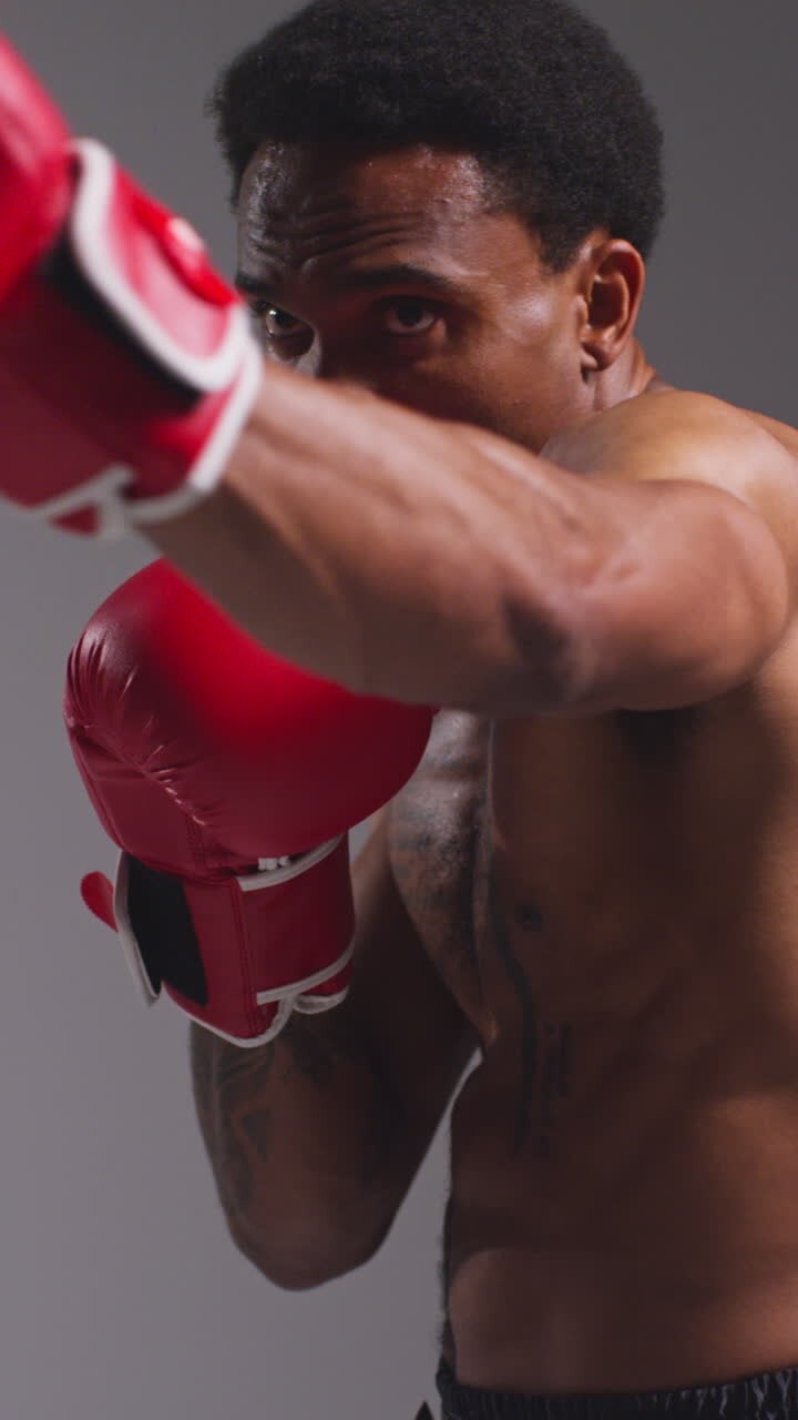Vertical Video Close Up Shot Of Tattooed Male Boxer Wearing Gloves In Boxing Match Throwing Punches At Opponent