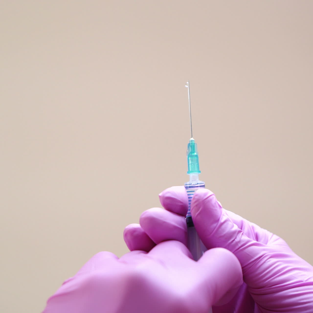 Close-up view on a cosmetologists hands in gloves holding syringe with needle for rejuvenating facial injections.