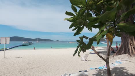 exotic island of koh hey (coral island) landscape view to idyllic shoreline and pier, crowded with tourists - wide slide gimbal shot
