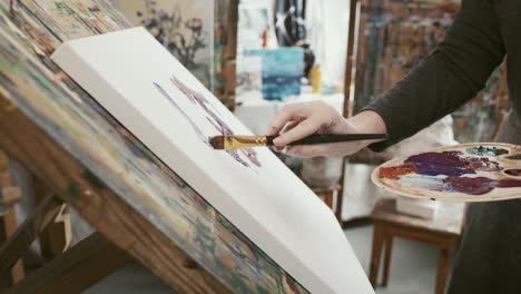 Mujer-Elegante-Usando-Pincel-Y-Paleta-Para-Dibujar-En-Un-Lienzo-Sostenido-Por-Un-Caballete