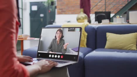 Mujer-Birracial-Usando-Una-Computadora-Portátil-Para-Videollamada,-Con-Un-Colega-De-Negocios-En-La-Pantalla