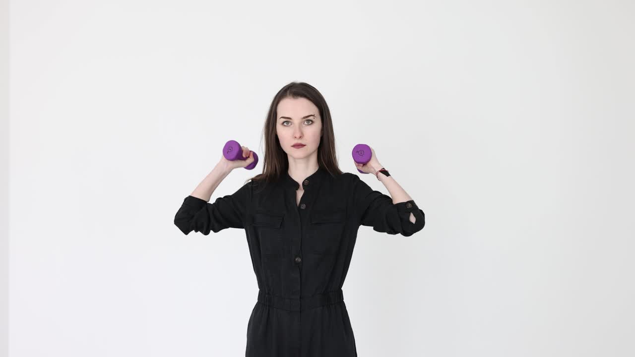Kvinde i sort jumpsuit løfter og sænker armene med håndvægte
