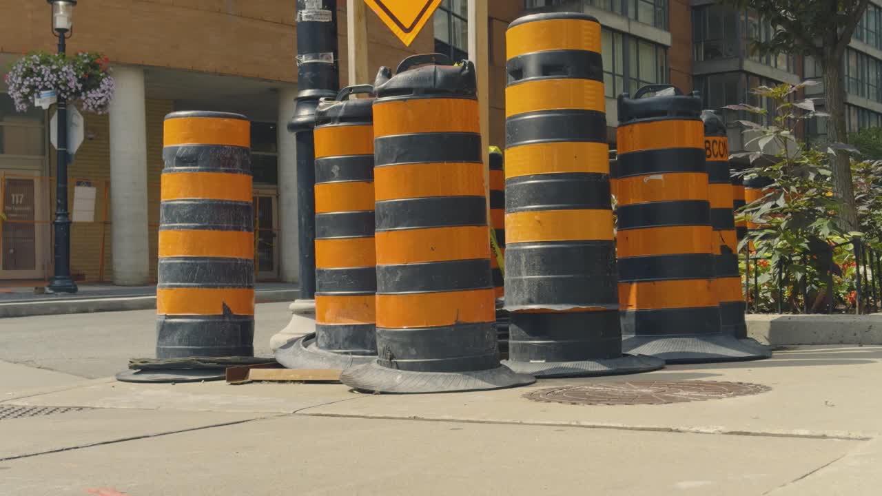 Black and orange construction cones on sidewalk, in an urban neighbourhood downtown Toronto