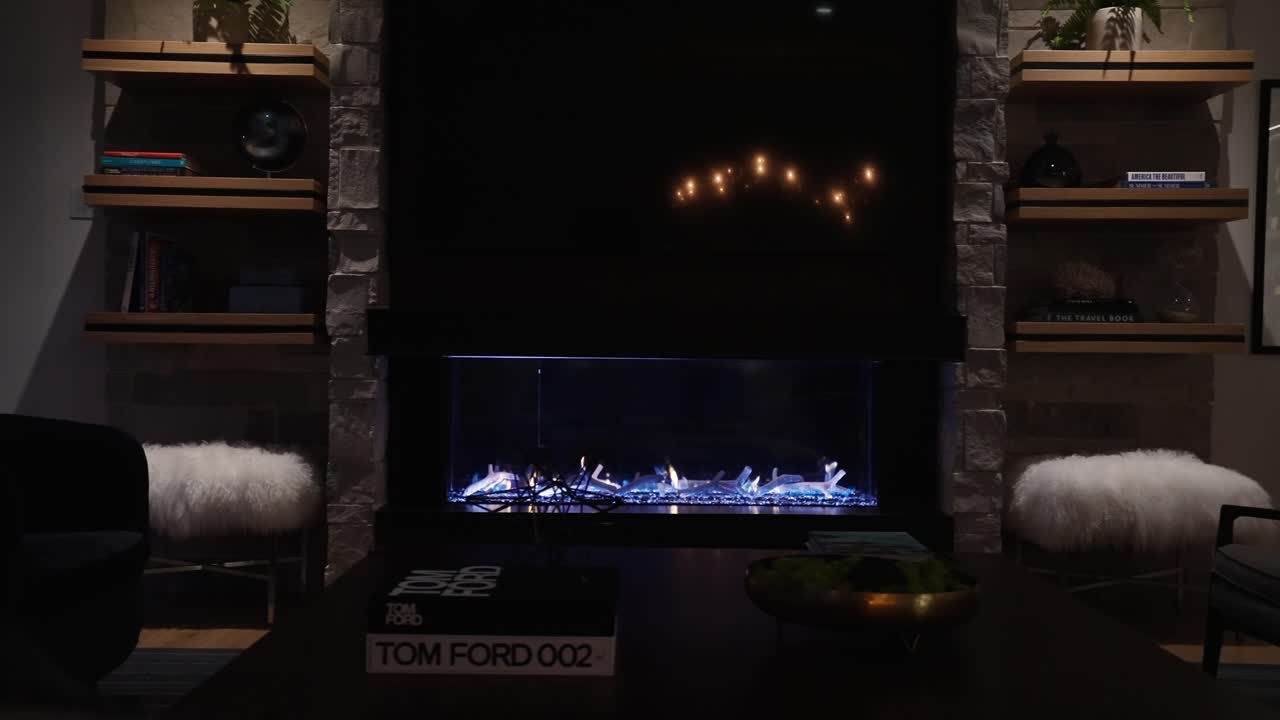 밤에 희미하게 조명 된 럭셔리 집 거실에서 파란색 억양으로 현대 가스 벽난로의  ⁇  촬영