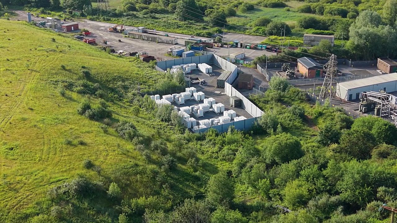Slow Orbit Aerial of Small Modular BESS Battery Energy Storage System with Lithium-ion Containers. Grid management, AI energy optimization, and sustainable infrastructure. UK. 4K.