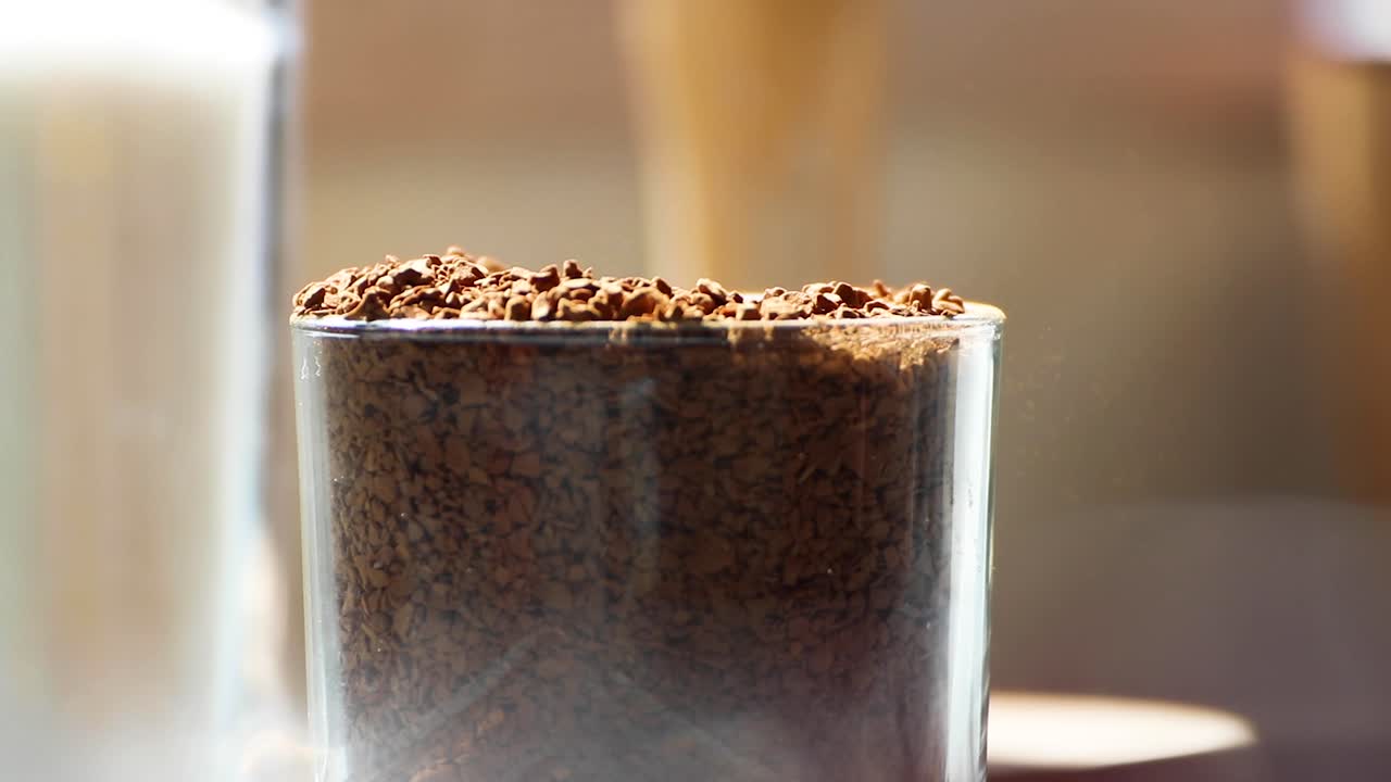 Teaspoon scooping coffee granules from glass jar