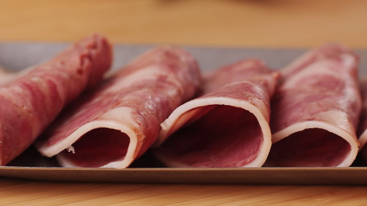 black bull sausage ham, tongue pork dry-cured sausage on a black background, traditional spanish delicatessen food, close up.