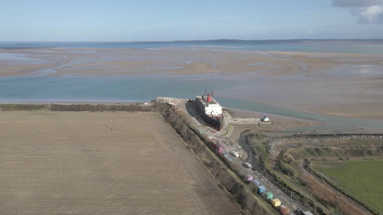 Vista aerea della nave Duke of Lancaster ormeggiata sulle rive dell'estuario gallese, a Llanerch-y-mor. Rotazione del drone verso destra che mostra l'estuario sullo sfondo
