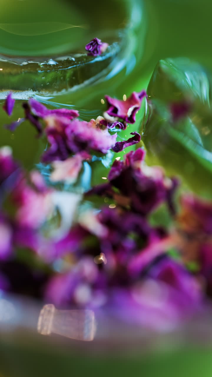 Close up of an iced matcha in a glass with purple dried flowers on top. Vertical