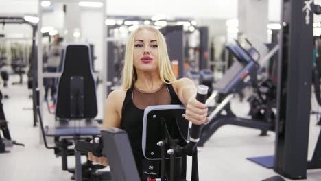 Young-female-bodybuilder-in-black-sportswear-doing-exersices-at-the-gym.-Building-up-strong-core-and-arms-muscles.-Frontside-footage