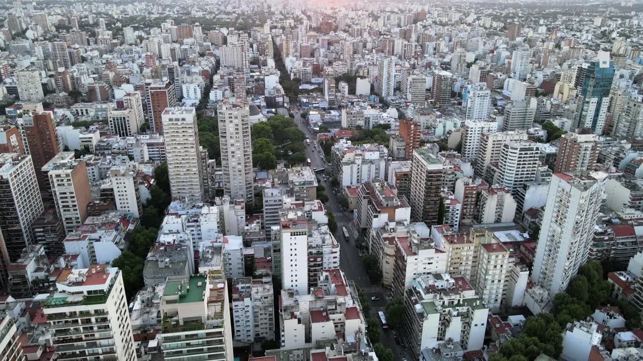 descenso aéreo sobre los edificios del barrio de belgrano al atardecer con sol brillante en el horizonte, buenos aires, argentina
