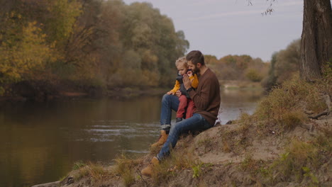 Familienwochenende-In-Der-Natur.-Mann-Und-Sein-Kleiner-Sohn-Sitzen-Am-Ufer-Des-Sees-Und-Entspannen-Sich,-Atmen-Frische-Luft-Und-Genießen-Das-Schöne-Herbstwetter