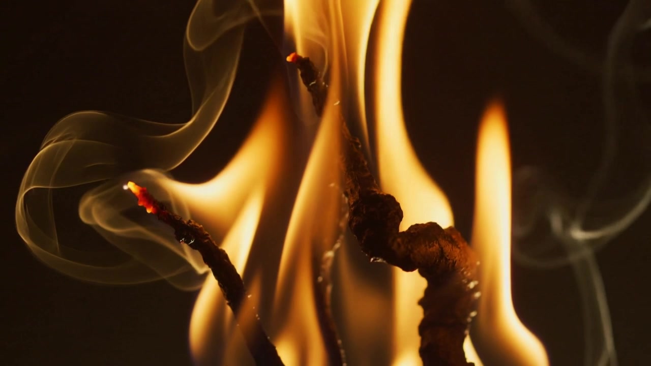 Sparking match tips burning in studio close-up for flame study, showing glowing embers and smoke