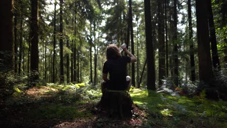 hiker enjoys a peaceful break in forest and drinks water