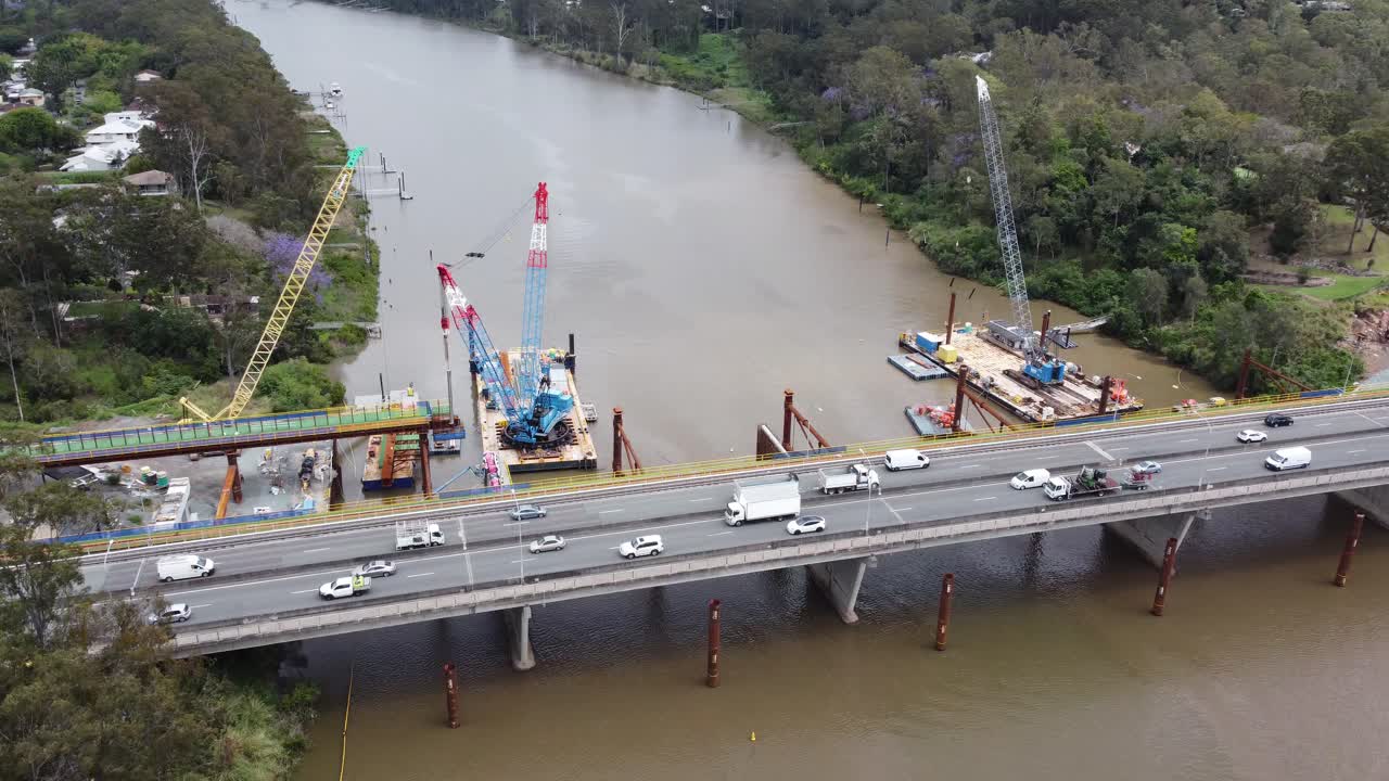Drone flying towards a new bridge construction site over a river