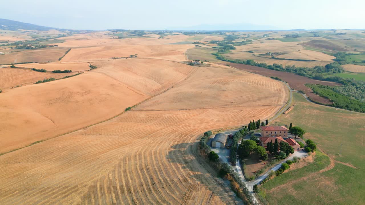 Sweeping golden fields surrounding weathered farmhouse nestled among rolling hills, capturing quintessential tuscan countryside landscape under bright summer sunlight