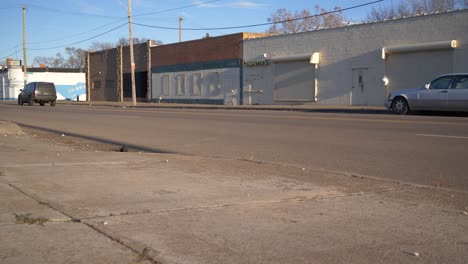 low angle dolly shot of a abandoned business on east side of detroit with cars passing by