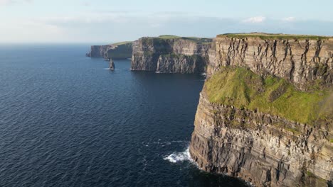 Los-Majestuosos-Acantilados-De-Moher-En-La-Costa-De-Irlanda,-Velero-En-El-Agua,-Luz-Del-Día,-Vista-Aérea