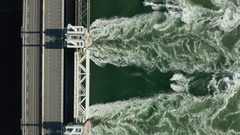 Top-View-Of-Floodgates-Of-Eastern-Scheldt-Storm-Surge-Barrier-Spilling-Water-In-Zeeland-Province,-Netherlands,-aerial