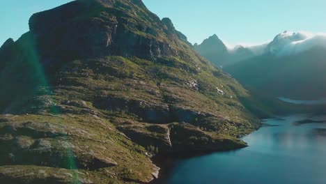 Schwenken,-Neigen-Nach-Unten-Drohnenaufnahme-Eines-Felsigen-Hügels-über-Einem-See-Auf-Den-Lofoten