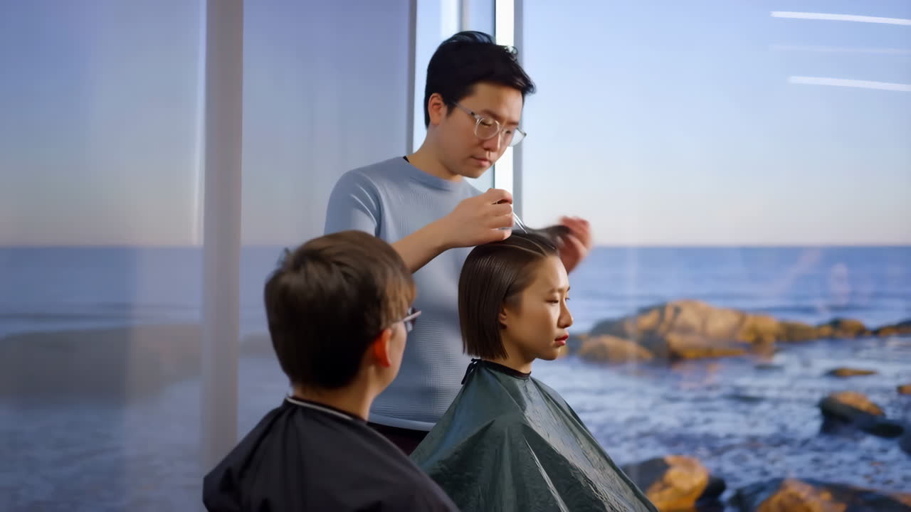 Hairdresser styling a customer's hair in a modern salon with a sea view