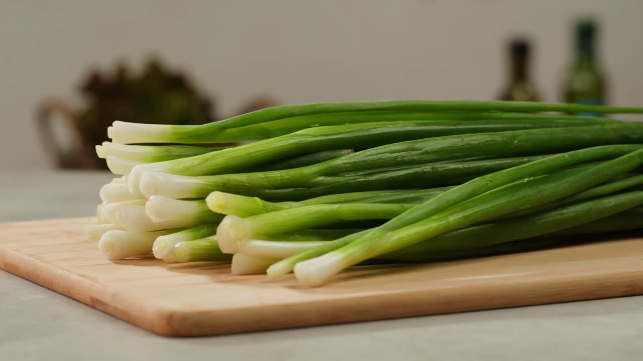 Cutting fresh green onions on a cutting board, close up chef cooking green vegan salad.