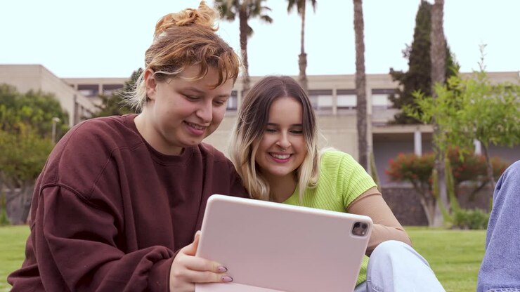 amigos alegres usando tableta en el campus de la universidad