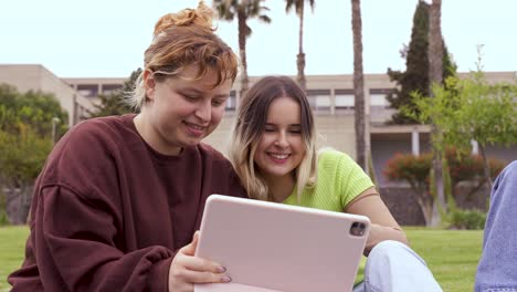 cheerful friends using tablet at university campus